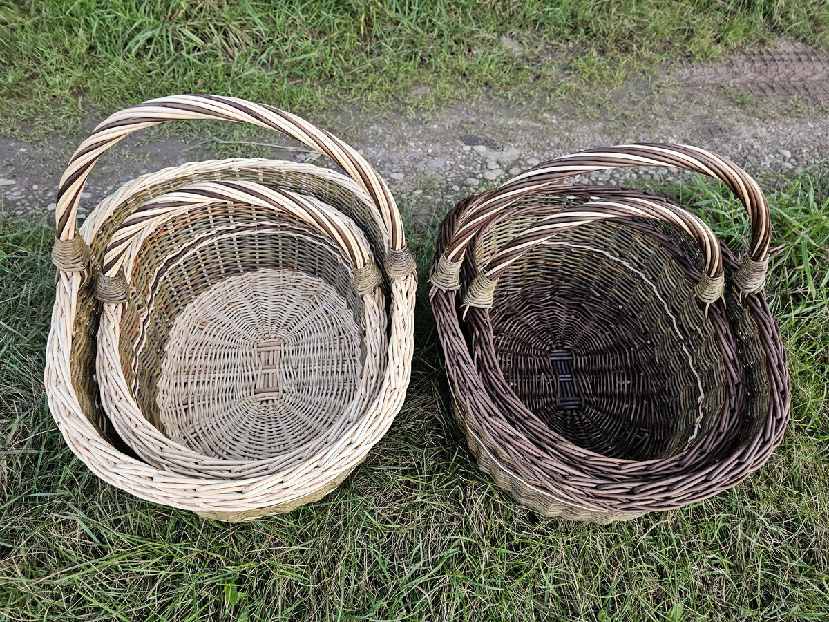 Top view of two sets of nesting wicker baskets on the grass, each small basket placed inside the large one.