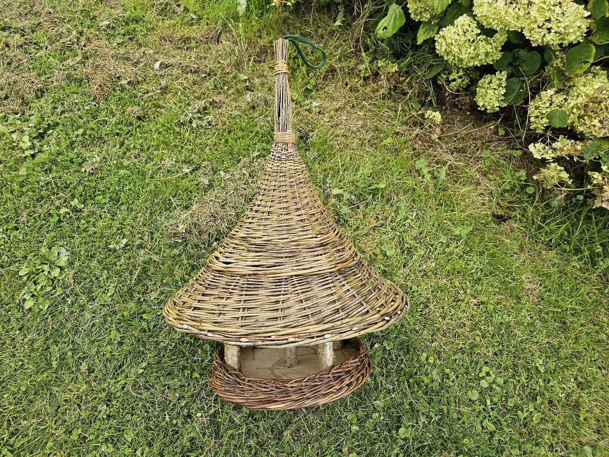 Willow wild bird feeder with a conical roof and hanging cord standing on a lawn, with the wooden seed platform visible below