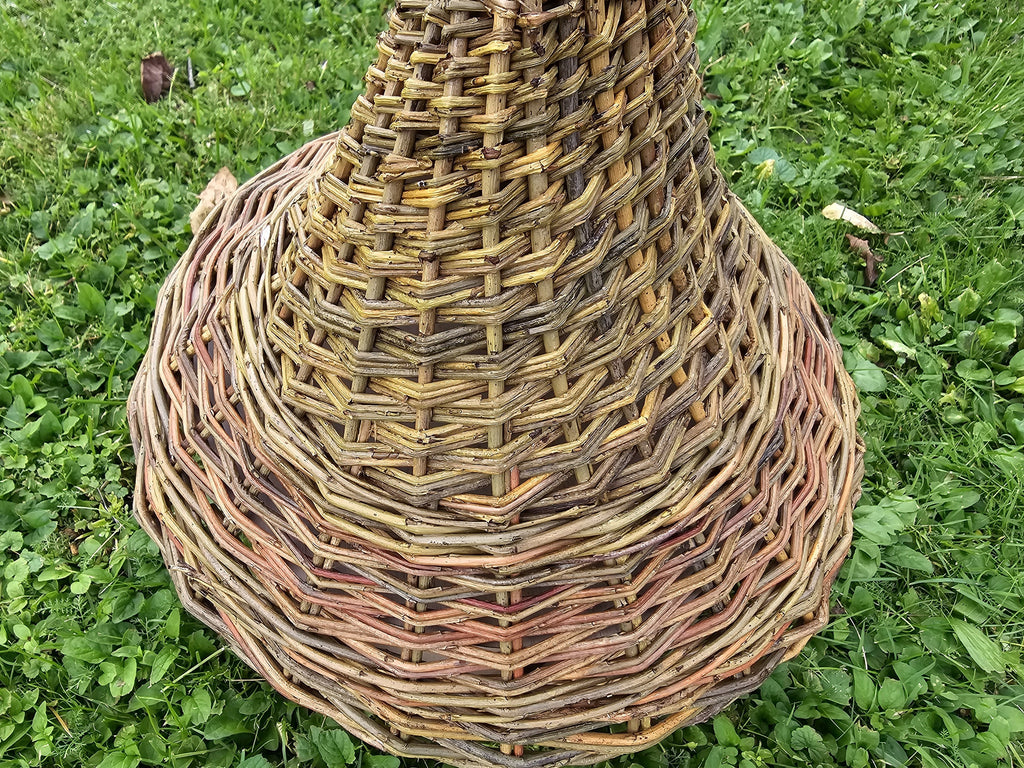 Close-up of the tightly woven bell-shaped willow roof of the tall bird feeder, showing the spiral weave