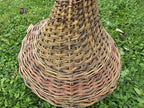 Close-up of the tightly woven bell-shaped willow roof of the tall bird feeder, showing the spiral weave