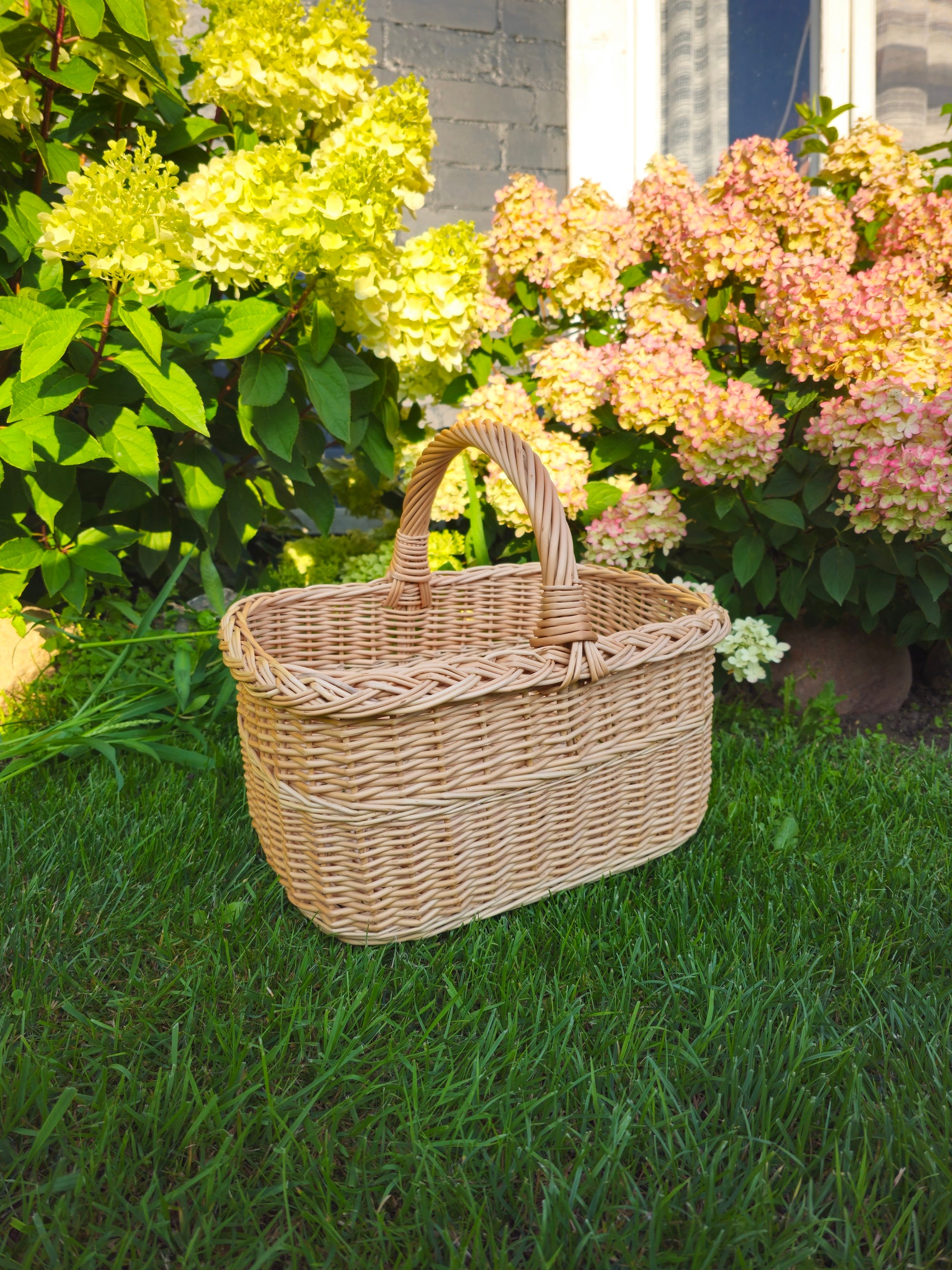 Wicker basket on a grassy area with flowers in the background