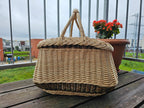 Side view of the handwoven willow garden basket with two handles and thick braided rim on a balcony table.