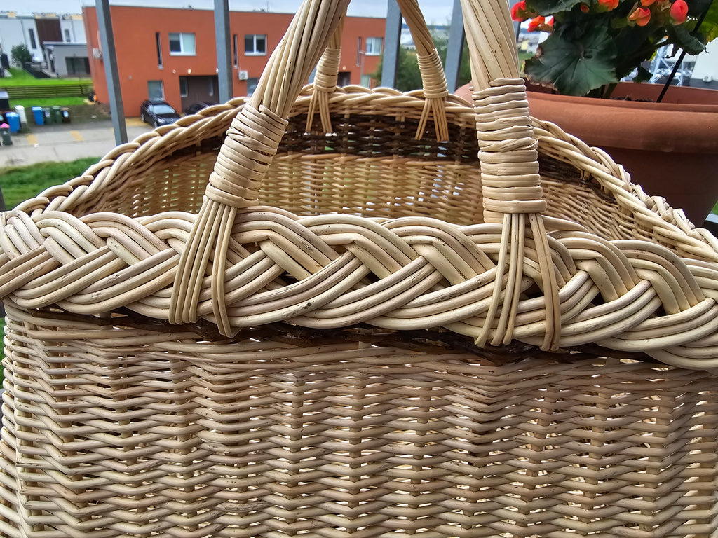 Close-up of the thick braided rim and the wrapped joins of the two crossed handles on a handwoven willow garden basket.