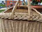 Close-up of the thick braided rim and the wrapped joins of the two crossed handles on a handwoven willow garden basket.