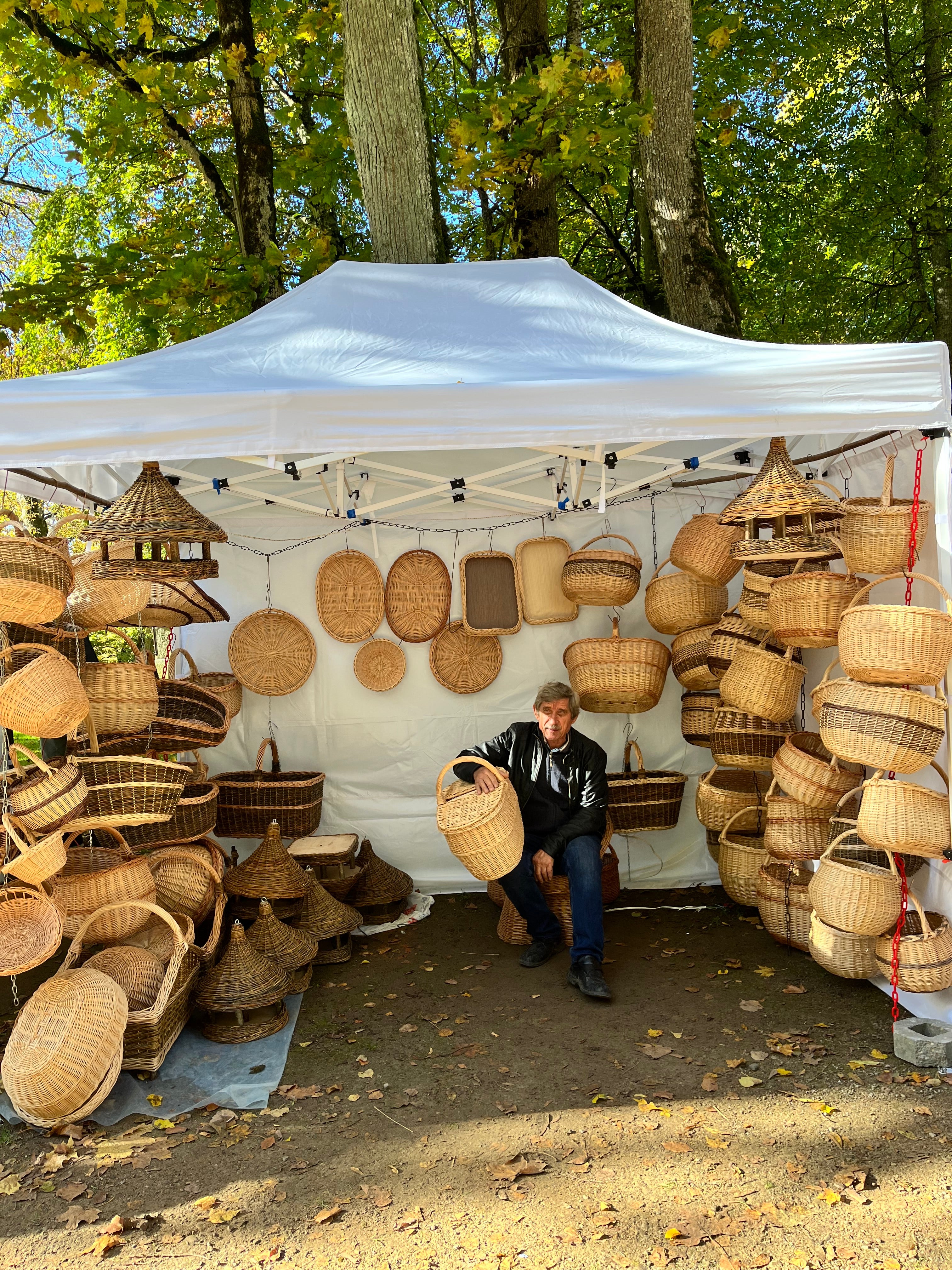 Wicker baskets displayed outdoors with a person standing among them.