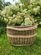 Wicker basket on grass with a background of green foliage and white flowers