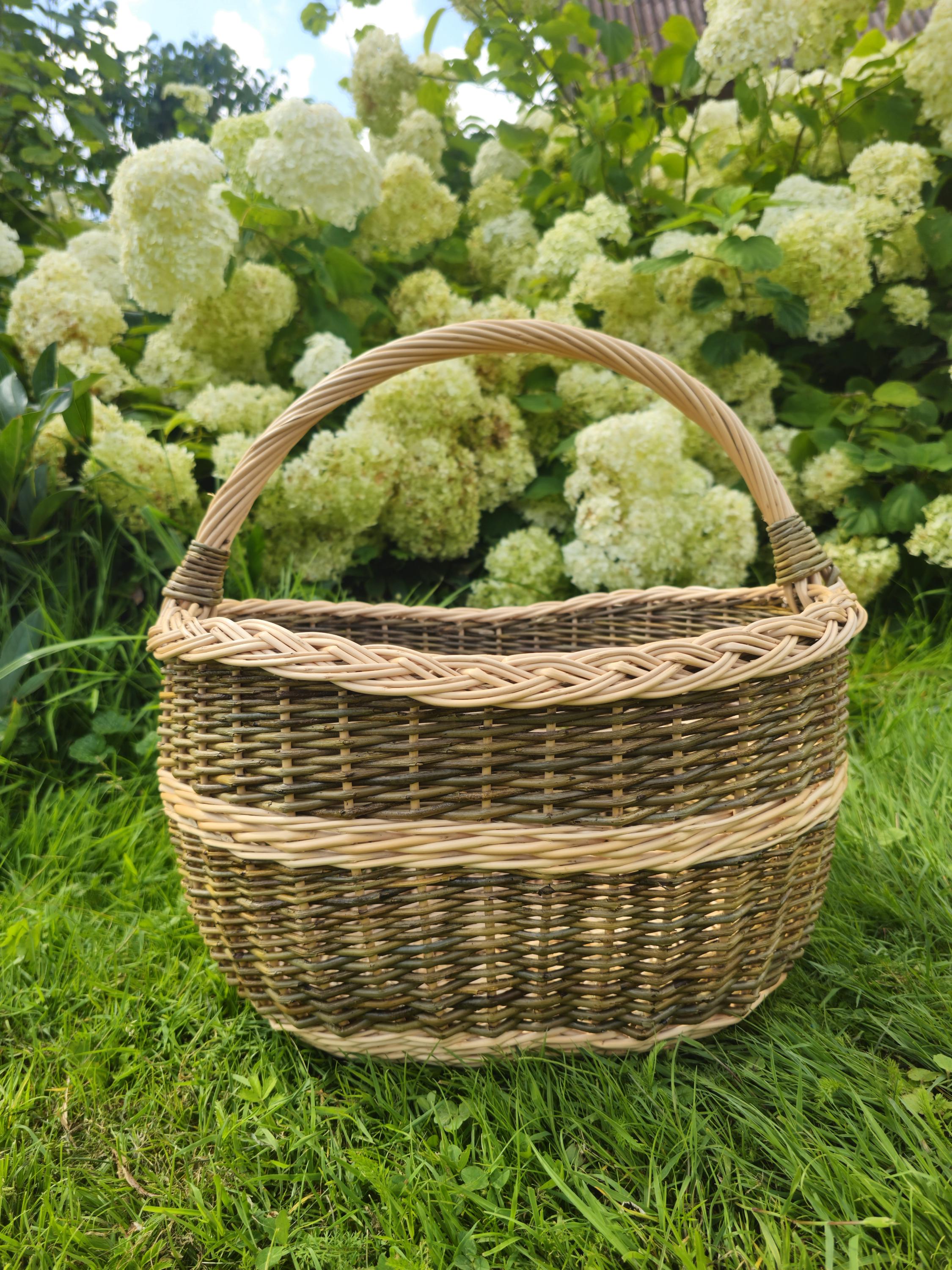Wicker basket on grass with a background of green foliage and white flowers