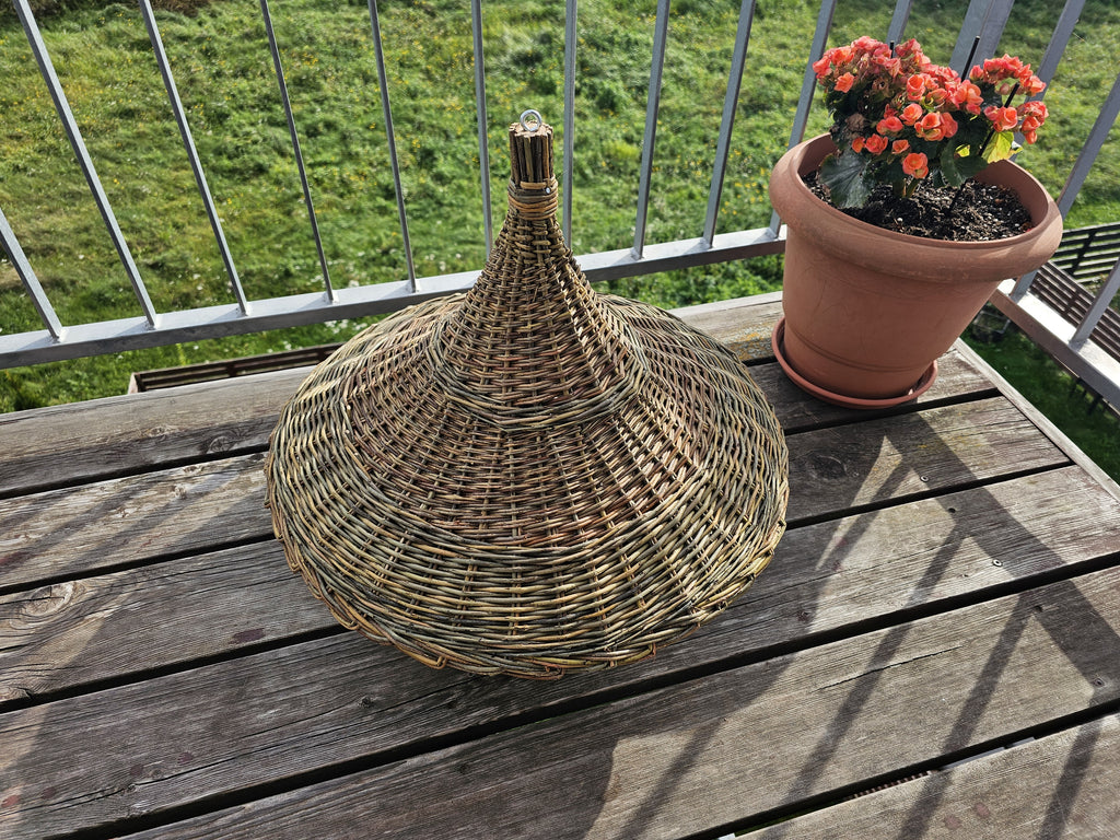 Side view of the woven willow roof of the extra large bird feeder, showing its tall cone shape flaring into a wide brim
