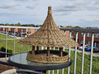 Extra large pagoda roof bird feeder on a balcony table, wide woven brim covering the whole feeding platform