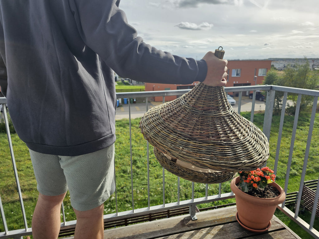 Man holding the extra large willow bird feeder by the hanging ring at the top, showing its size