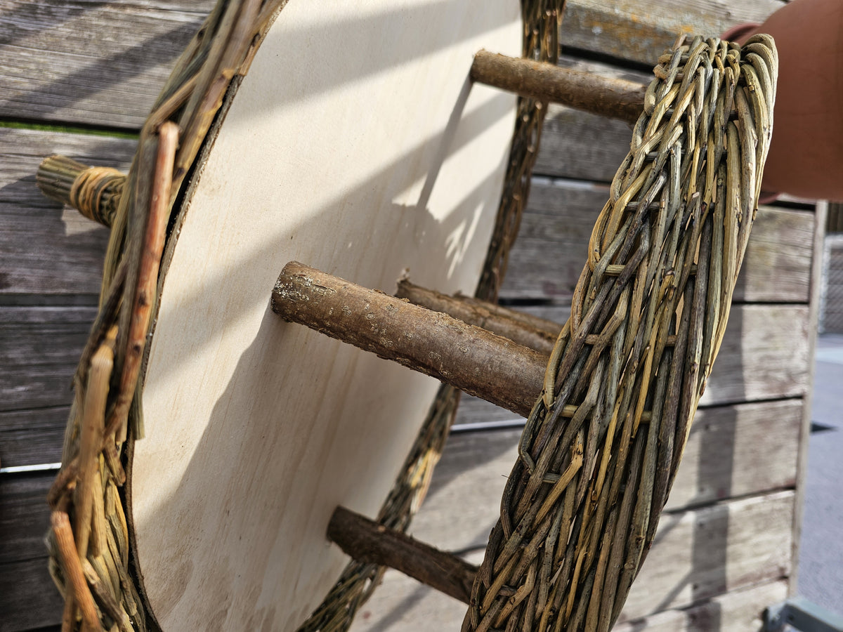 Close-up of bark-on branch posts fixed between the wooden roof disc and the wooden platform of the willow bird feeder