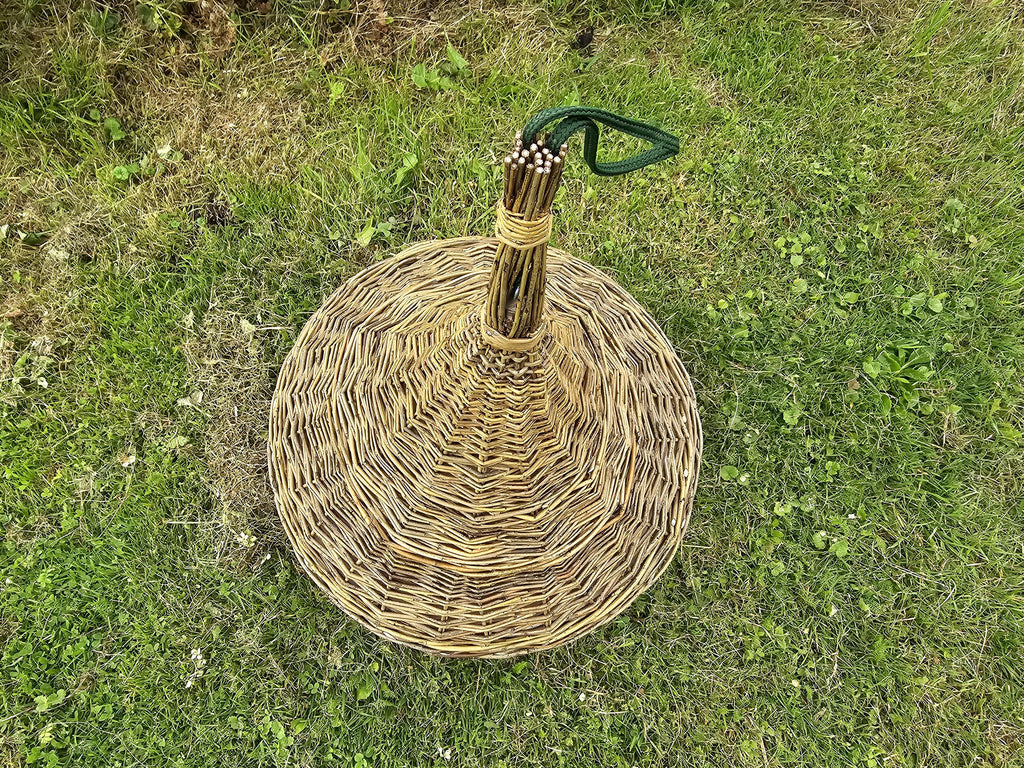 Top view of the willow bird feeder's woven conical roof with the bundled willow peak and green hanging cord, lying on the grass
