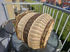 Oval willow basket lying on its side on a glass table to show the woven base and the braided rim