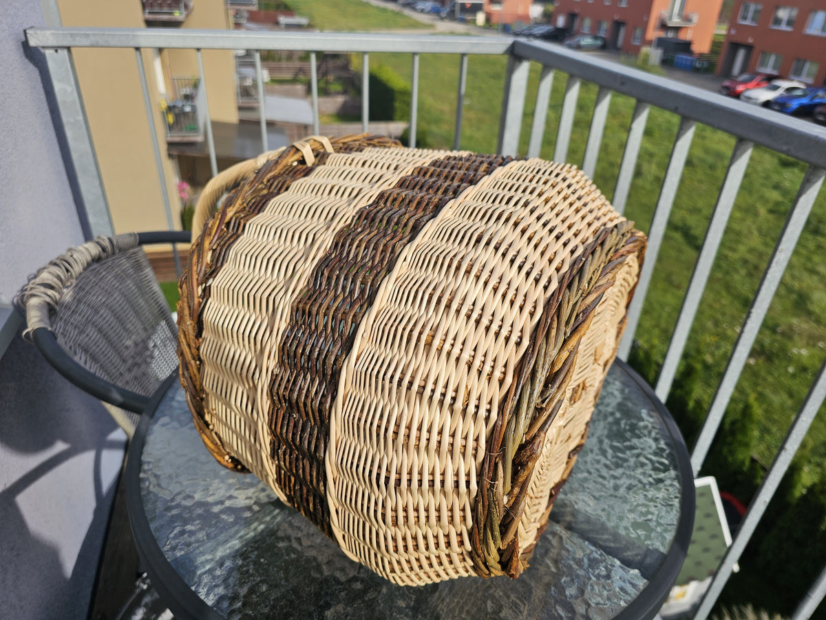 Oval willow basket lying on its side on a glass table to show the woven base and the braided rim