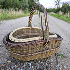 Two handwoven willow baskets on a gravel path, the smaller one resting inside the larger