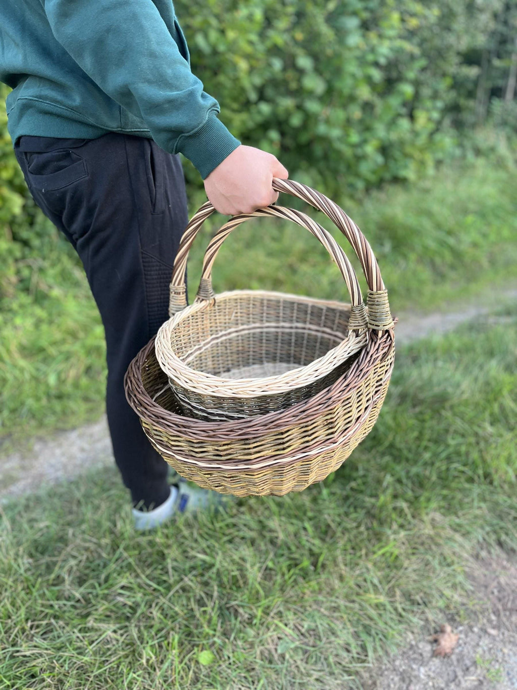 Both baskets carried in one hand along a grassy path, showing how they travel together