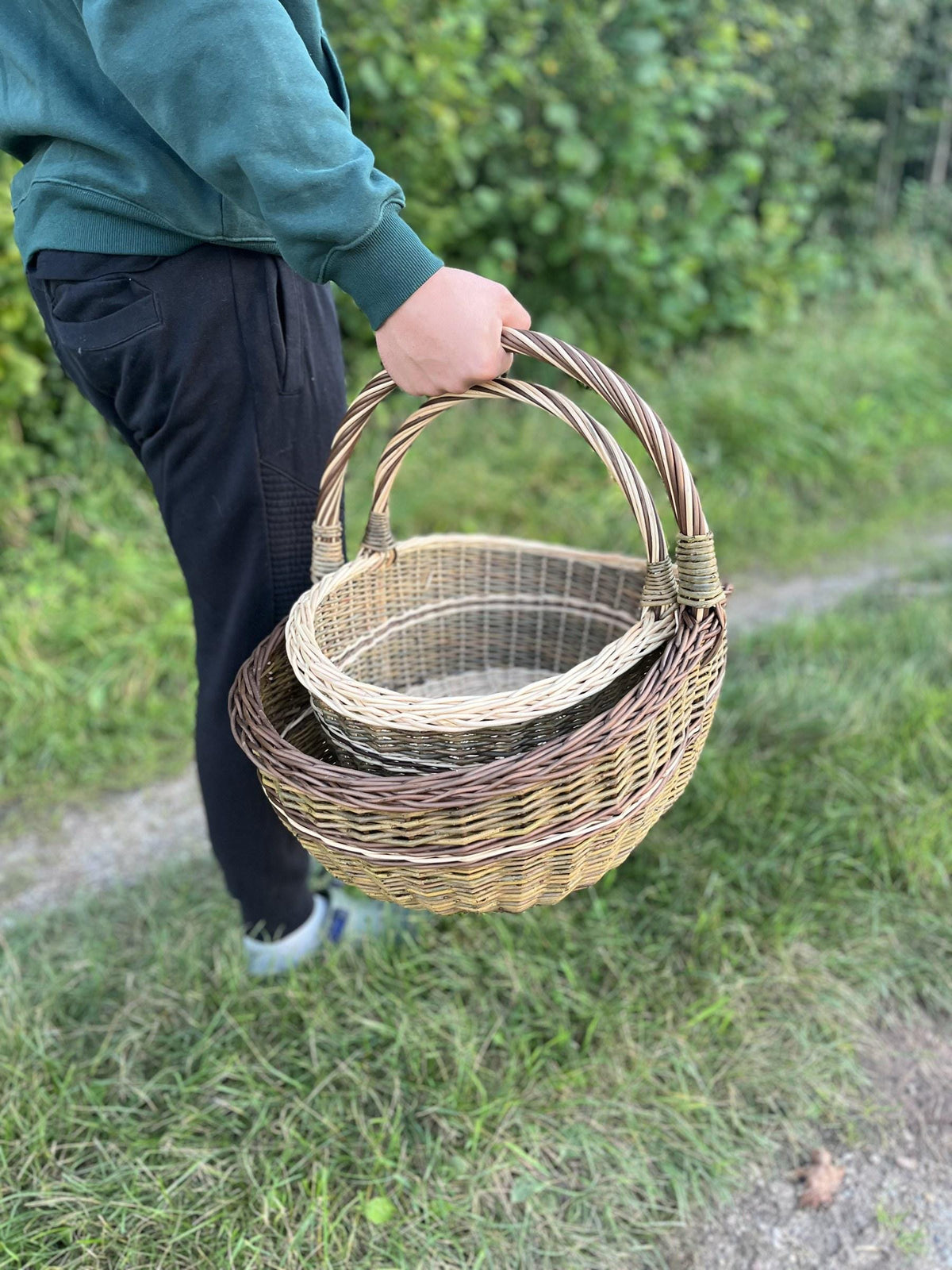 Both baskets carried in one hand along a grassy path, showing how they travel together