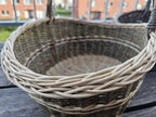 Close-up of the plaited rim and woven interior of the smaller basket from the set of two nesting willow trugs on a balcony table.