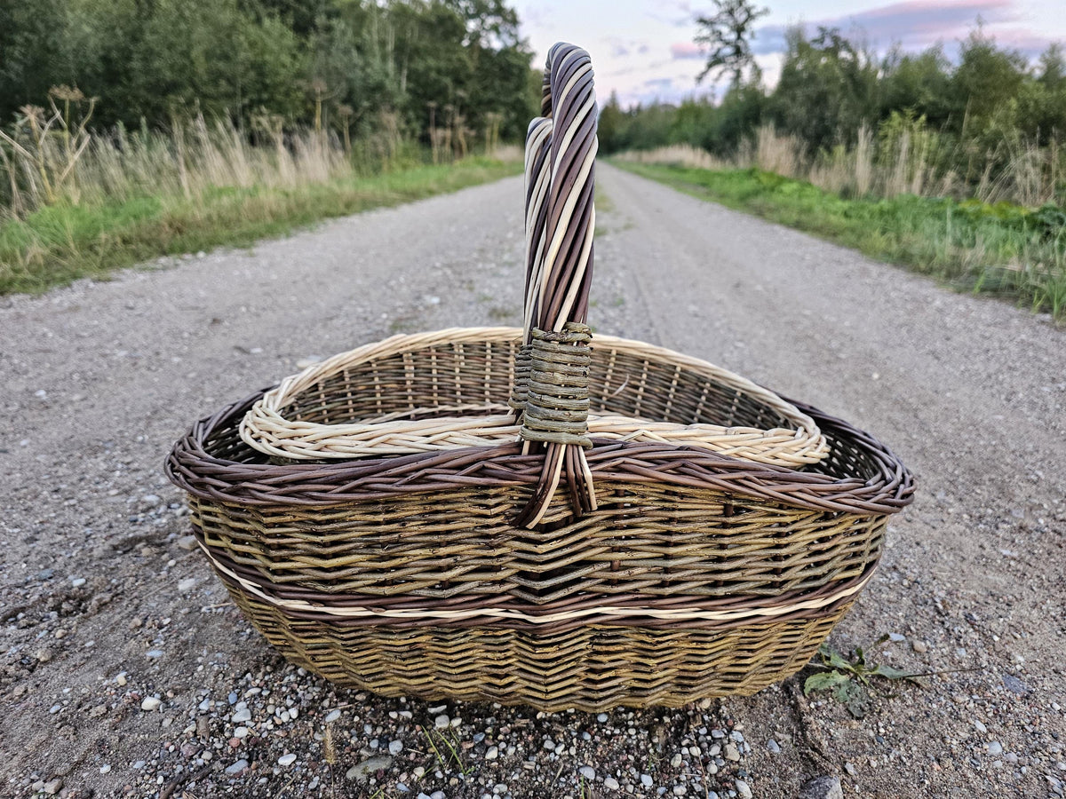 Set of 2 nesting wicker baskets on a long gravel road, the smaller trug sitting inside the larger with both twisted handles upright.