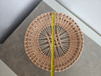 Round openwork willow tray with a tape measure across it on a grey table