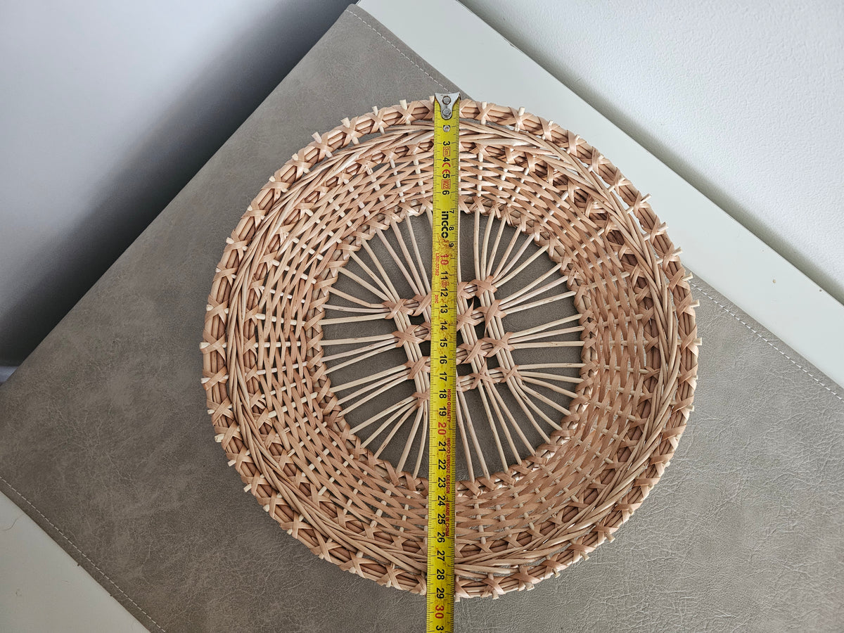 Round openwork willow tray with a tape measure across it on a grey table