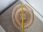 Oval lace-weave willow tray measured with a tape on a grey table
