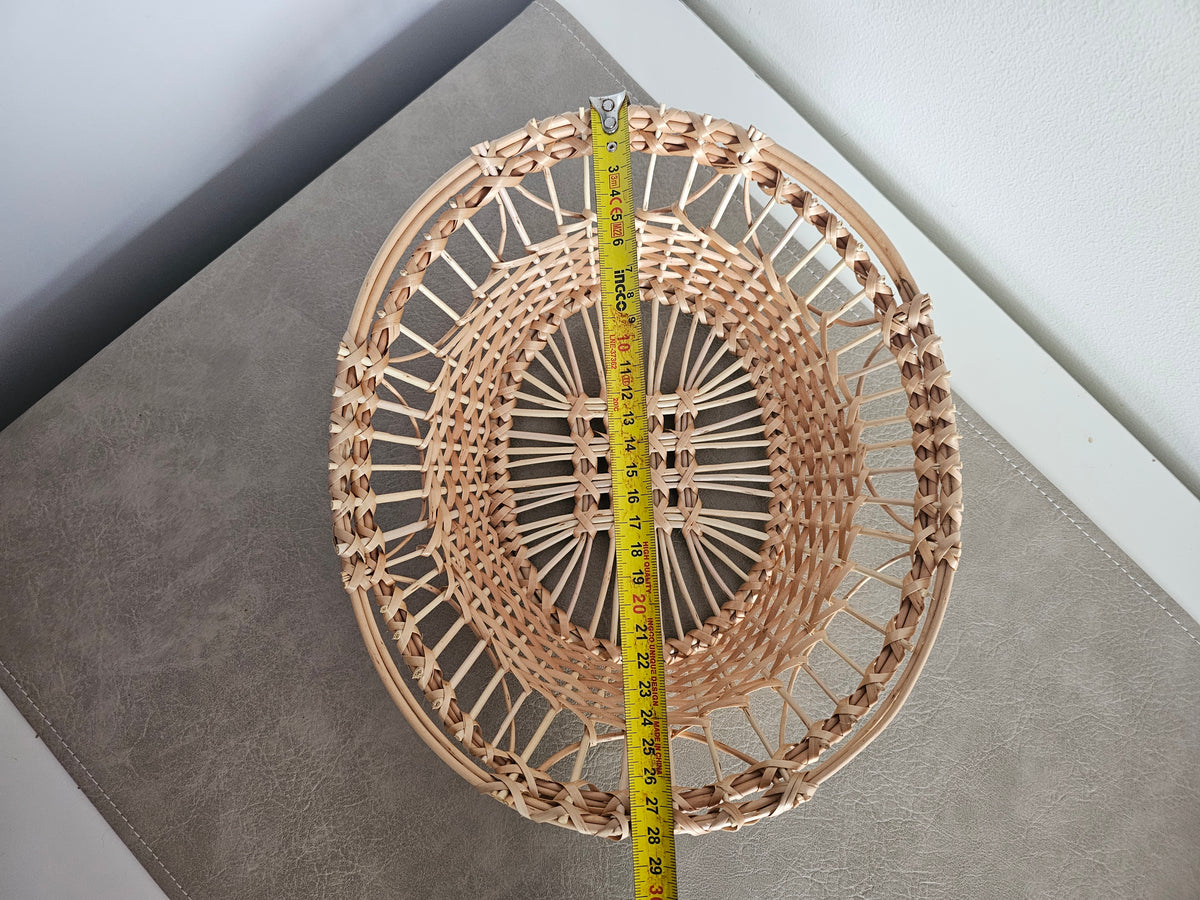 Oval lace-weave willow tray measured with a tape on a grey table