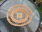 Round openwork willow tray with a lattice centre and plaited rim, seen from above on a glass table