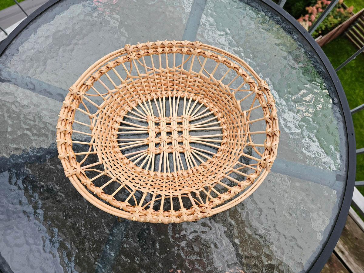 Round openwork willow tray with a lattice centre and plaited rim, seen from above on a glass table
