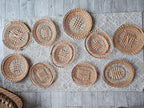 Ten handwoven openwork willow trays with different patterns laid out together on a rug