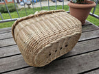 Underside of the large oval willow market basket turned upside down on a wooden table, showing the sturdy woven base