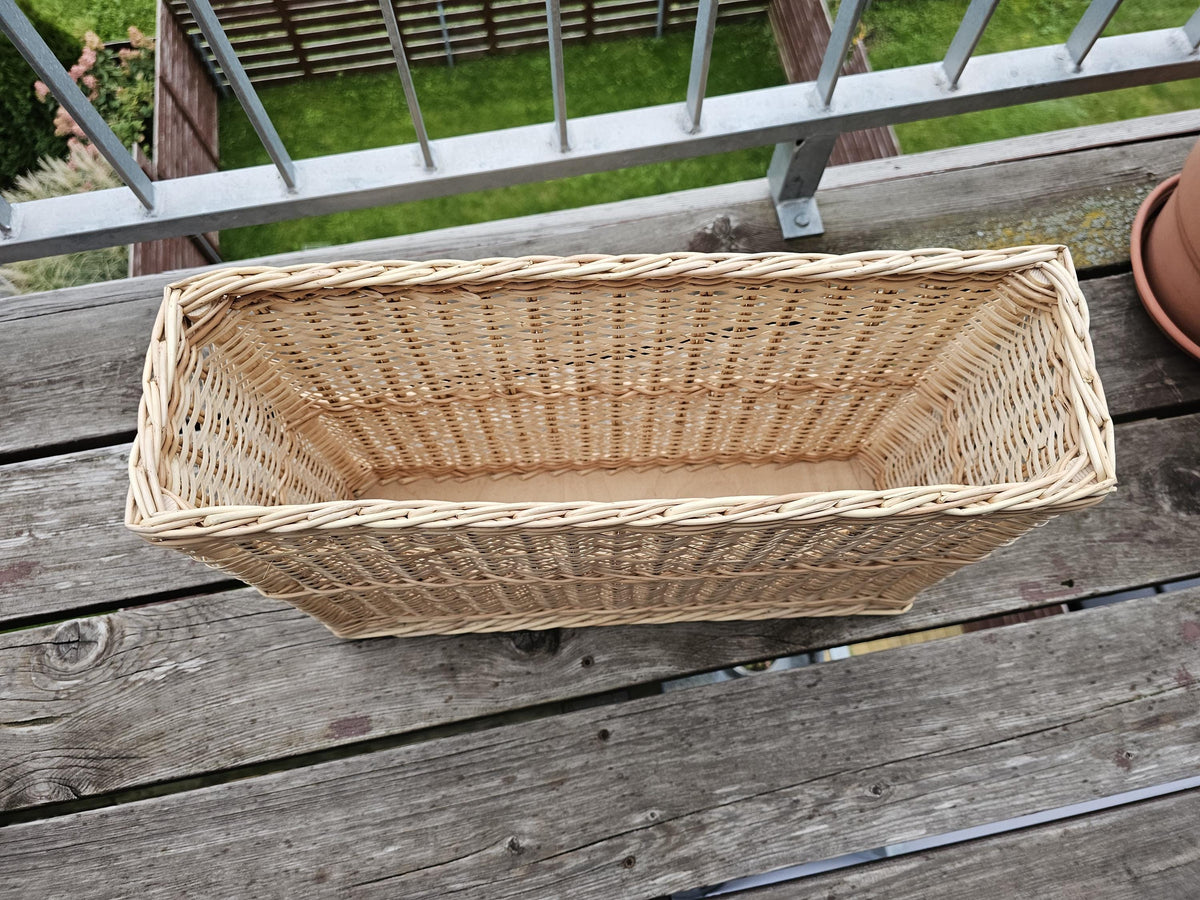 Narrow willow storage basket seen from above, showing its long slim shape and wooden base