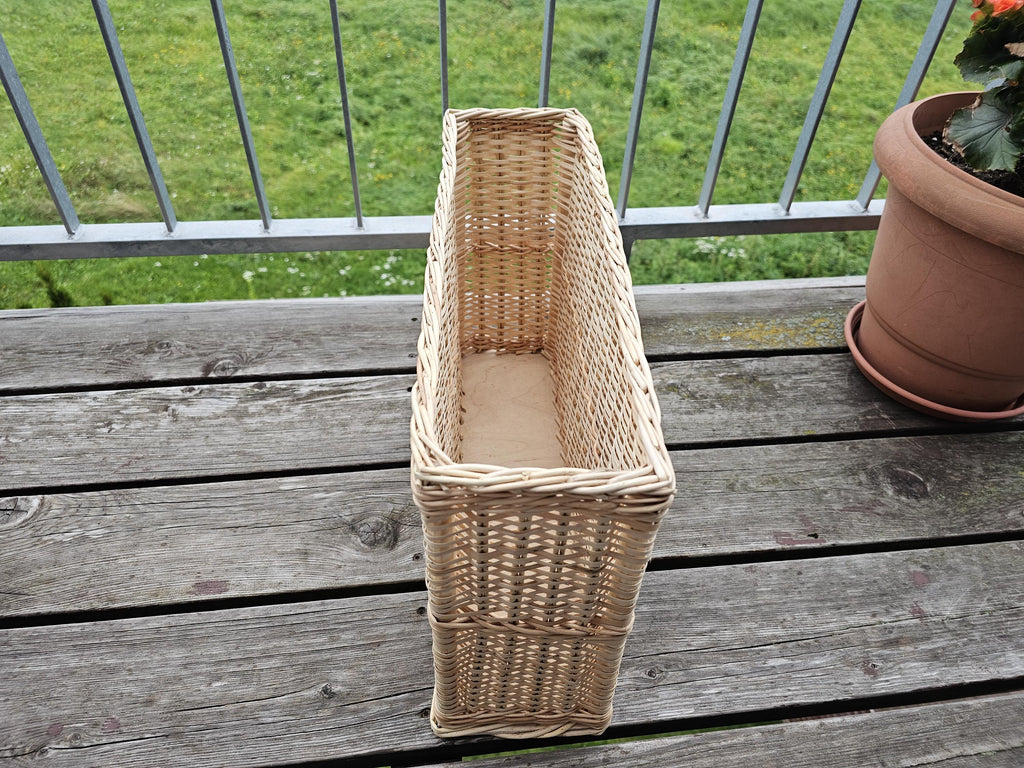 Narrow willow storage basket, 45 × 12 × 26 cm, standing end-on on a wooden table, showing its slim shape