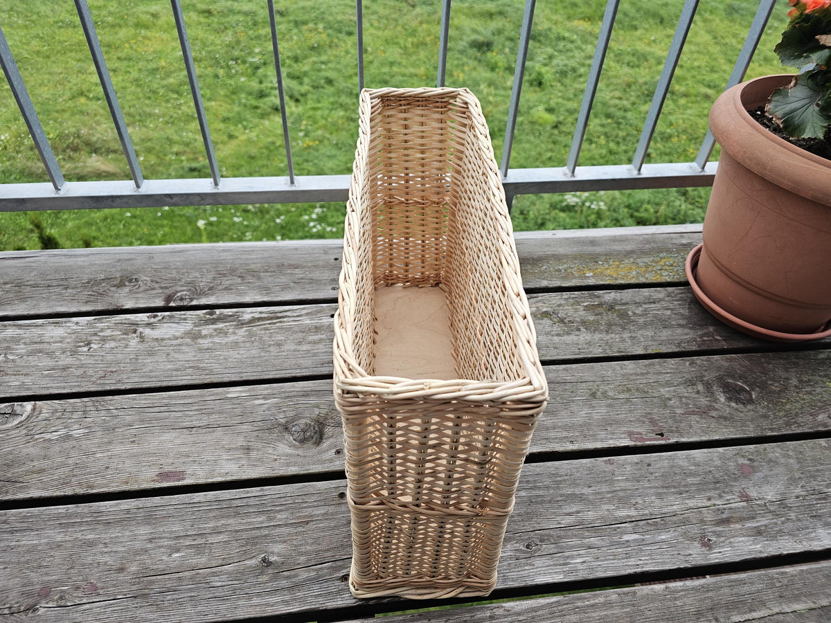Narrow willow storage basket, 45 × 12 × 26 cm, standing end-on on a wooden table, showing its slim shape