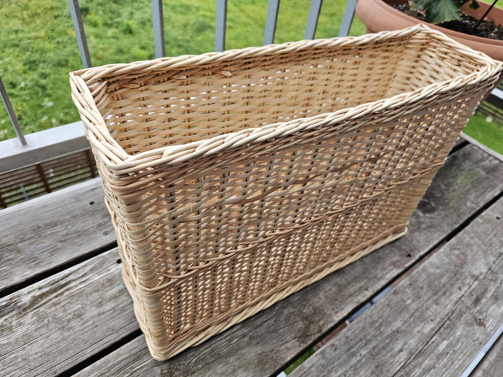 Narrow rectangular willow basket from the side, showing the raised woven bands and plaited rim