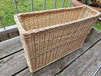 Narrow rectangular willow basket from the side, showing the raised woven bands and plaited rim