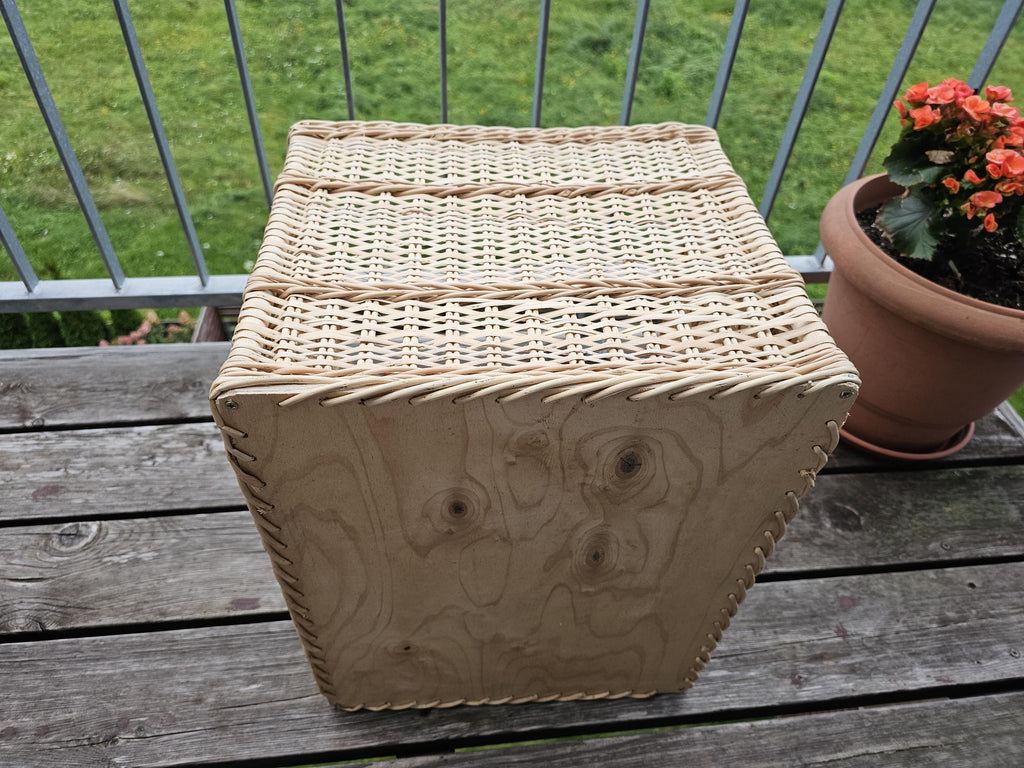 Underside of the large willow storage basket showing the solid wooden board base