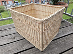 Large rectangular willow storage crate in a three-quarter view on a balcony table