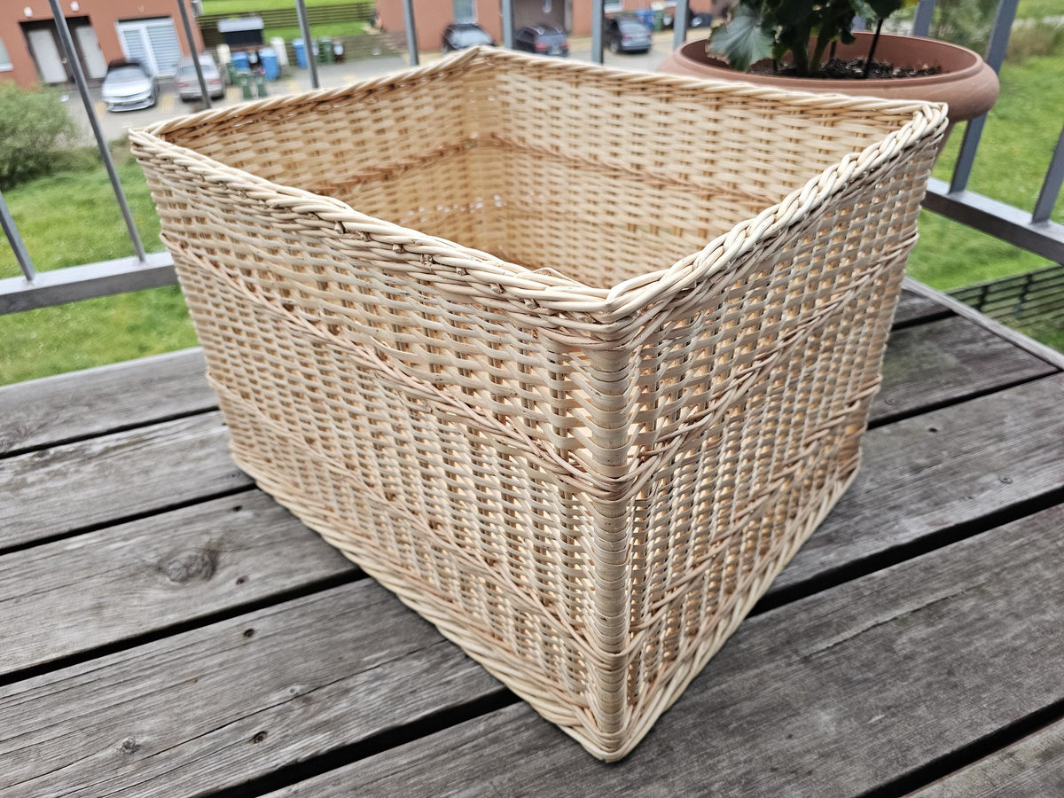 Large rectangular willow storage crate in a three-quarter view on a balcony table