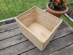 Large willow storage basket viewed from above at an angle, showing the wooden board base inside
