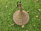 Top view of the woven bell-shaped roof of the willow bird feeder lying on grass, showing the tied spire of willow rods