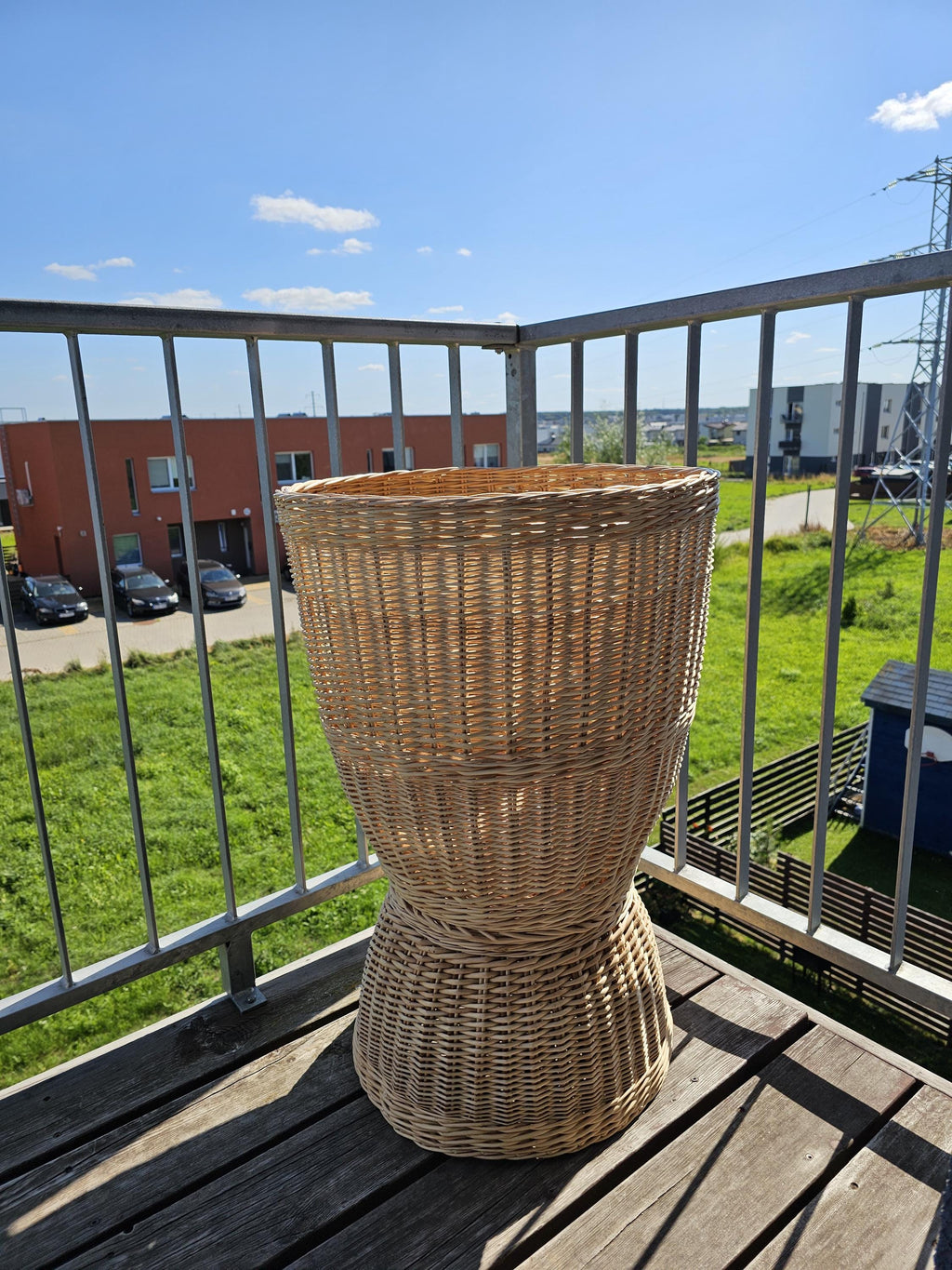 Tall willow floor basket with a distinctive hourglass silhouette, tapering from the wide rim into a narrow waist before expanding to a broad base.