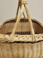 Close-up of the thick plaited edge and twin twisted willow handles on a traditional Lithuanian foraging basket.