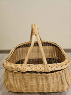 Front view into a handwoven wicker harvest basket, showing the deep braided rim, inner weave and two crossed willow handles.