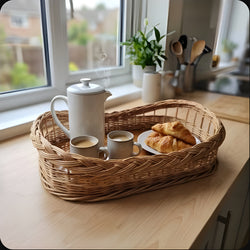 Kleines Serviertablett aus Weide mit Holzboden, darauf Kaffeekanne, zwei Becher und Croissants, auf der Küchenarbeitsplatte am Fenster