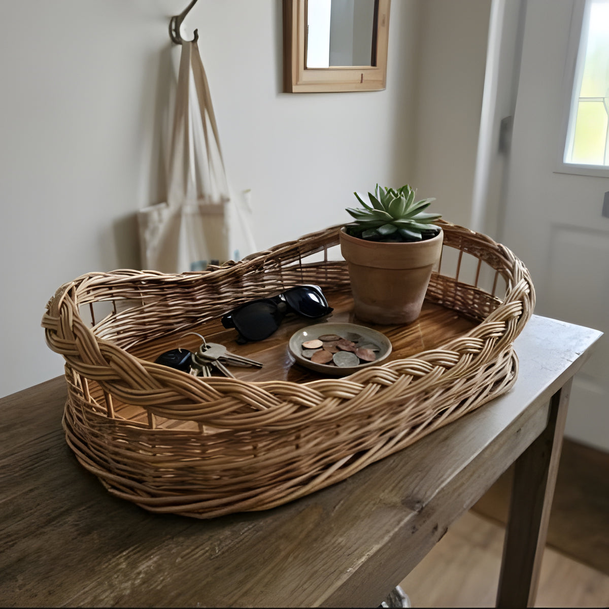 Wicker catch-all tray with wooden base holding keys, sunglasses, coins and a succulent on a hallway table by the door